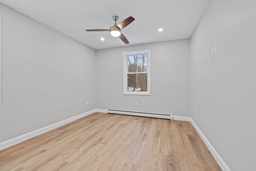 Empty room with white walls and wood floors and a ceiling fan