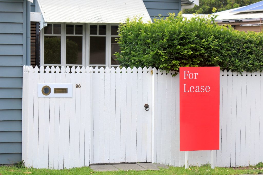 Red For Lease sign on a house in the rental property market